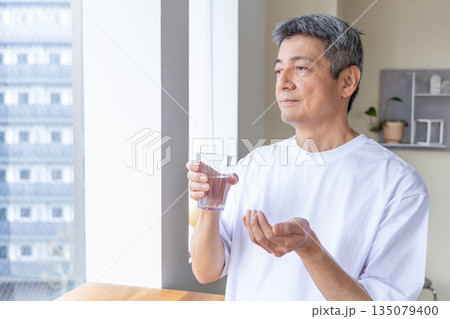 窓辺で薬を飲むシニア男性 135079400