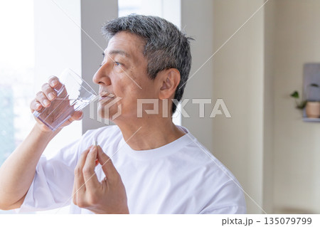 窓辺で薬を飲むシニア男性 135079799