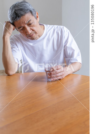 水を持って頭を抱えるシニア男性 135080196