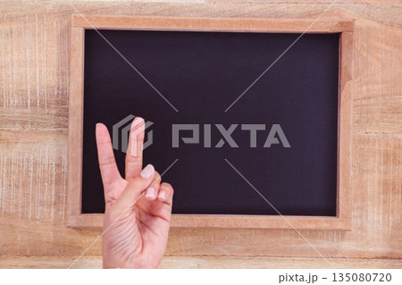 Flat design wooden-framed chalkboard with hand making V sign is being shown on wooden panel Flat design wooden-framed chalkboard with hand making V sign is being shown on wooden panel 135080720