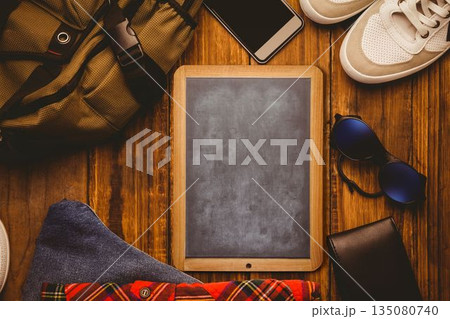 Chalkboard tablet is being shown in flat lay on wooden surface with backpack, phone and sneakers Chalkboard tablet is being shown in flat lay on wooden surface with backpack, phone and sneakers 135080740