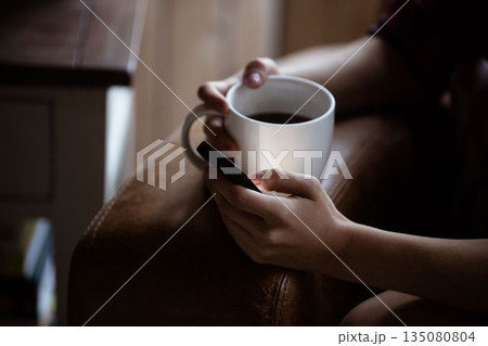 Mid section of woman using mobile phone while having coffee Mid section of woman using mobile phone while having coffee 135080804