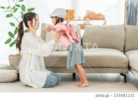 自宅のリビングで娘の着替えを手伝う母親 135081133