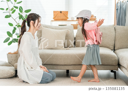 自宅のリビングで娘の着替えを手伝う母親 自宅のリビングで娘の着替えを手伝う母親 135081135