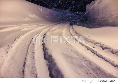 雪道に残るタイヤの跡　深夜の雪道に灯るやさしい街灯 135081362