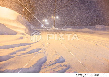 雪道に残るタイヤの跡　深夜の雪道に灯るやさしい街灯 135081365