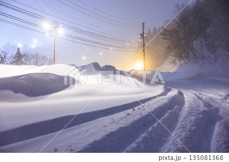 雪道に残るタイヤの跡　深夜の雪道に灯るやさしい街灯 135081368