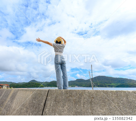 女性が海辺で手を広げる 【撮影協力：隠岐シーサイドリゾートみやび様】 135082342