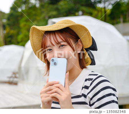 麦わら帽子とスマホを持つ女性 【撮影協力:隠岐シーサイドリゾートみやび様】 麦わら帽子とスマホを持つ女性 【撮影協力:隠岐シーサイドリゾートみやび様】 135082348