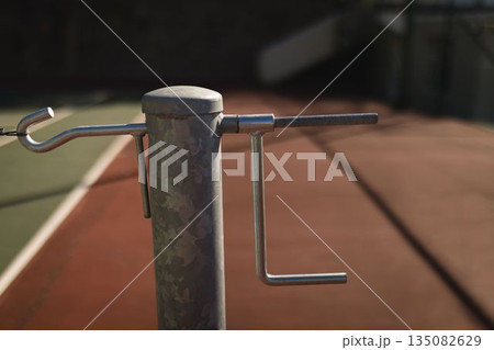 Flat design showing cylindrical net post with horizontal rod and L-shaped crank on clay court 135082629