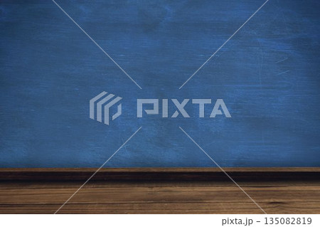 Blue chalkboard is sitting above wooden ledge and desk in classroom showing chalk smudges 135082819
