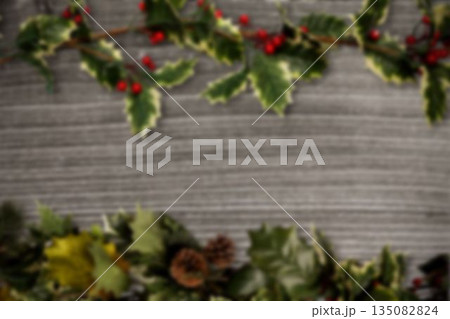 Rustic plank is framing holly branches with berries and pine cones in flat style, copy space 135082824