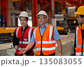 Three industrial engineers wearing safety uniform walk and discuss operations inside heavy factory, representing leadership, teamwork, and communication in high-risk industrial. 135083055
