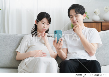 スマートフォンを操作する妊婦と夫 ライフスタイルイメージ スマートフォンを操作する妊婦と夫 ライフスタイルイメージ 135083132