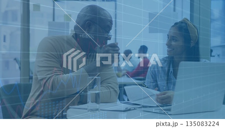 Discussing senior man and woman reviewing documents at office table with data charts overlay 135083224