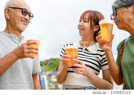 三世代で乾杯、屋外でビール 【撮影協力:隠岐シーサイドリゾートみやび様】 三世代で乾杯、屋外でビール 【撮影協力:隠岐シーサイドリゾートみやび様】 135083325
