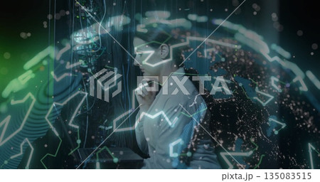 IT engineer in lab coat examining server racks, cables, LEDs and holographic globe in data center 135083515