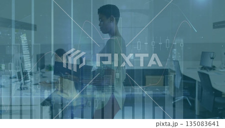 Reading colleague wearing fitted sweater and slacks in office, holding binder with financial charts 135083641