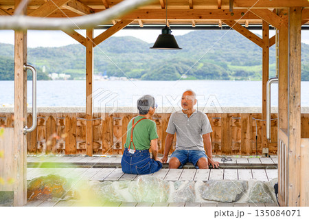 海辺で足湯を楽しむ夫婦 【撮影協力：隠岐シーサイドリゾートみやび様】 135084071