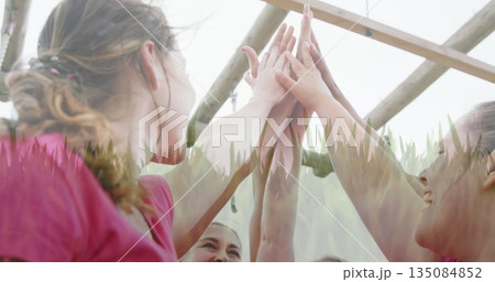 Stretching women raising arms and touching palms under monkey bars, wearing pink shirts and earbud Stretching women raising arms and touching palms under monkey bars, wearing pink shirts and earbud 135084852