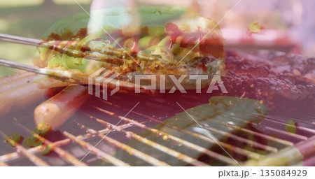 Grilling hot dog bun with cheese, jalapeños on grill in backyard, alongside sausages and meat slab 135084929