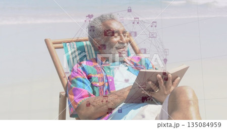 Reclining senior man holding paperback on sandy beach near shoreline, with digital icons Reclining senior man holding paperback on sandy beach near shoreline, with digital icons 135084959