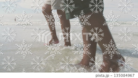 Walking father and son in swim trunks splashing waves in shallow ocean water on sandy seabed Walking father and son in swim trunks splashing waves in shallow ocean water on sandy seabed 135084967