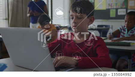 Typing boy wearing red shirt working on silver laptop at classroom desk, with teacher guiding Typing boy wearing red shirt working on silver laptop at classroom desk, with teacher guiding 135084992
