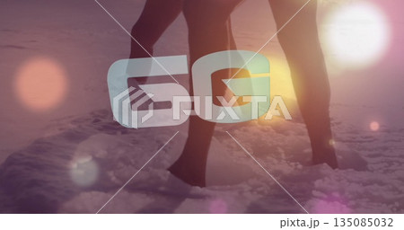 Standing couple wearing swimwear in shallow water on shore at sunset, with 5G overlay, lens flares 135085032
