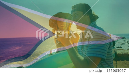 Laughing men wearing striped shirt holding surfboard, sipping drink at rocky shore with ocean waves Laughing men wearing striped shirt holding surfboard, sipping drink at rocky shore with ocean waves 135085067