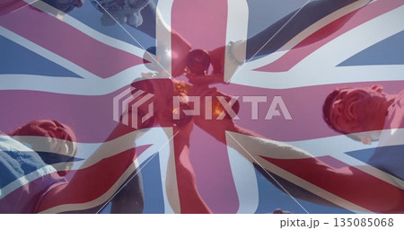 Raising group of five friends holding amber glass bottles under clear blue sky, Union Jack overlay Raising group of five friends holding amber glass bottles under clear blue sky, Union Jack overlay 135085068
