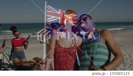 Friends cooking skewers on barbecue grill at sandy beach, with beer bottles and Union Jack flag Friends cooking skewers on barbecue grill at sandy beach, with beer bottles and Union Jack flag 135085125