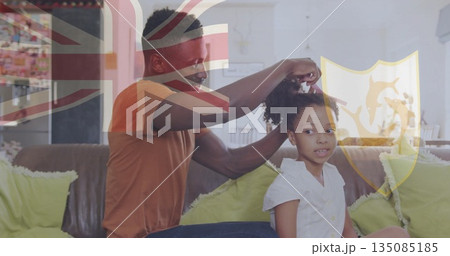 Combing daughter curly hair in living room, father using hairbrush with British flag overlay 135085185