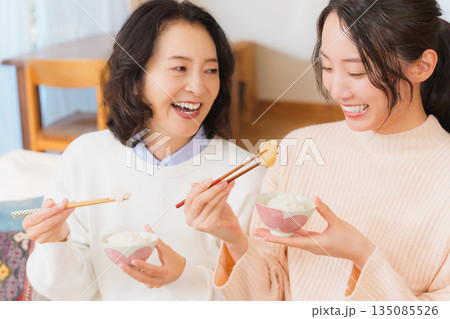 おいしいねと言って笑顔で顔を合わせる母と娘 135085526