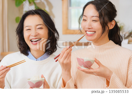 おいしいねと言って笑顔で顔を合わせる母と娘 135085533