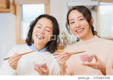 おいしいねと言って笑顔で顔を合わせる母と娘 135085560