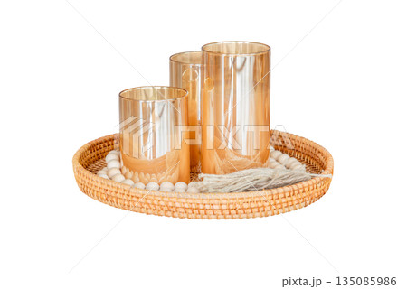 A bunch of candles in dark glass bottles on a beautiful wicker tray. Soft focus. Photo on white background. Isolated object. A bunch of candles in dark glass bottles on a beautiful wicker tray. Soft focus. Photo on white background. Isolated object. 135085986