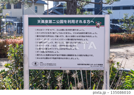 公園利用に関する禁止事項やマナー（犬の散歩・ボール遊び・花火禁止など）が記載された注意看板 135086010