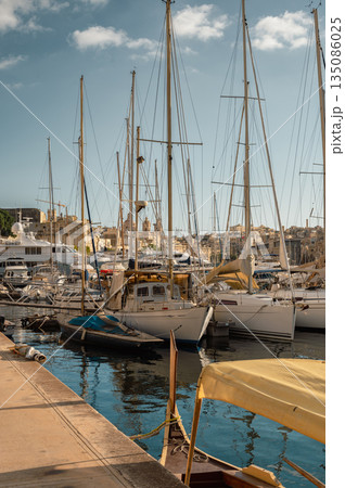 A picturesque view of Birgu Port filled with numerous boats, bathed in warm pre-sunset light. The tranquil waters reflect the golden hues, creating a serene maritime scene in Malta. A picturesque view of Birgu Port filled with numerous boats, bathed in warm pre-sunset light. The tranquil waters reflect the golden hues, creating a serene maritime scene in Malta. 135086025