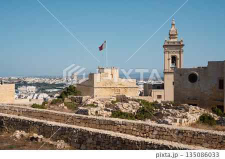 A breathtaking panoramic view of Gozo Island, showcasing its rolling hills, historic architecture, and stunning coastline under the Mediterranean sun. A breathtaking panoramic view of Gozo Island, showcasing its rolling hills, historic architecture, and stunning coastline under the Mediterranean sun. 135086033