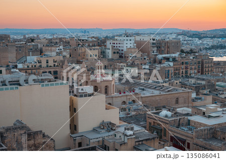 A stunning aerial view of Valletta's rooftops, showcasing the city's historic architecture, domes, and limestone buildings under the Mediterranean sky. A stunning aerial view of Valletta's rooftops, showcasing the city's historic architecture, domes, and limestone buildings under the Mediterranean sky. 135086041