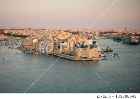 A stunning panoramic view of Birgu Port as seen from a Valletta vantage point, showcasing historic architecture, docked boats, and the scenic Maltese coastline. A stunning panoramic view of Birgu Port as seen from a Valletta vantage point, showcasing historic architecture, docked boats, and the scenic Maltese coastline. 135086049