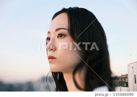 夕暮れ 屋上にいる女性のポートレート 135086090