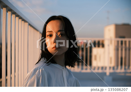 夕暮れ 屋上にいる女性のポートレート 135086207