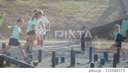 Navigating children and instructor crossing low-level obstacle course at camp, wooden posts 135086373
