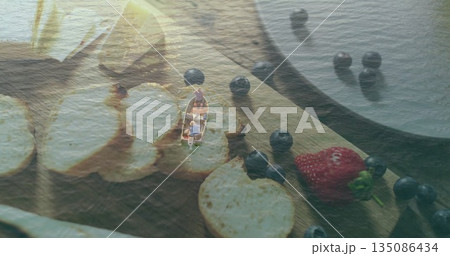 Men in rowboat rowing on calm lake, with cutting board holding bread slices blueberries strawberry Men in rowboat rowing on calm lake, with cutting board holding bread slices blueberries strawberry 135086434