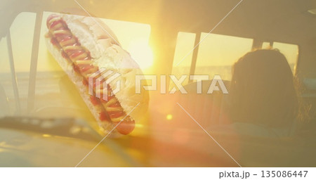 Floating hot dog dripping mustard and ketchup above car dashboard inside cabin, golden ocean sunset Floating hot dog dripping mustard and ketchup above car dashboard inside cabin, golden ocean sunset 135086447