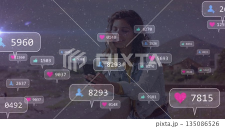 Holding smartphone, woman wearing denim jacket engaging with floating social icons in desert canyon Holding smartphone, woman wearing denim jacket engaging with floating social icons in desert canyon 135086526