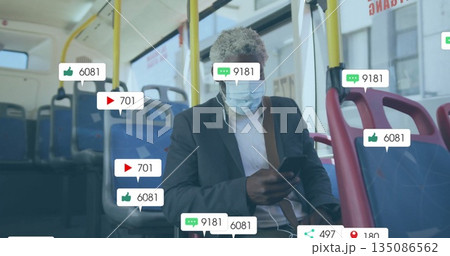 Holding smartphone, commuter wearing suit and mask on transit bus, with floating notifications Holding smartphone, commuter wearing suit and mask on transit bus, with floating notifications 135086562