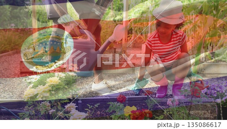 Watering girl kneeling and father tipping cans in backyard garden with raised beds Watering girl kneeling and father tipping cans in backyard garden with raised beds 135086617